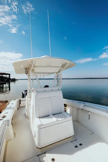  Yacht Photos Pics 2006 Yellowfin 31 CC boat with white seating, docked by calm waters under a clear blue sky.