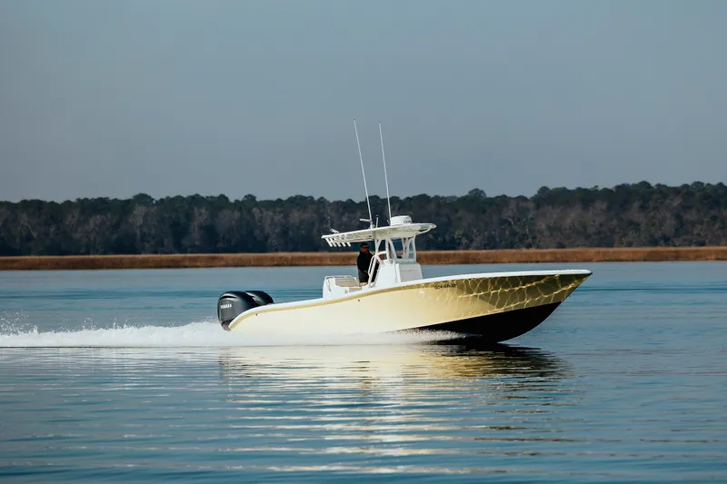  Yacht Photos Pics 2006 Yellowfin 31 CC boat cruising on calm water with forested shoreline.