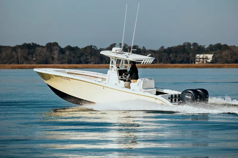  Yacht Photos Pics 2006 Yellowfin 31 CC boat cruising on calm water with trees in the background.