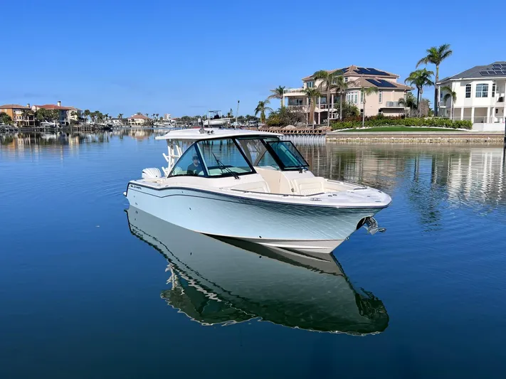  Yacht Photos Pics 2023 Grady-White Freedom 325 boat on calm water near luxury waterfront homes.