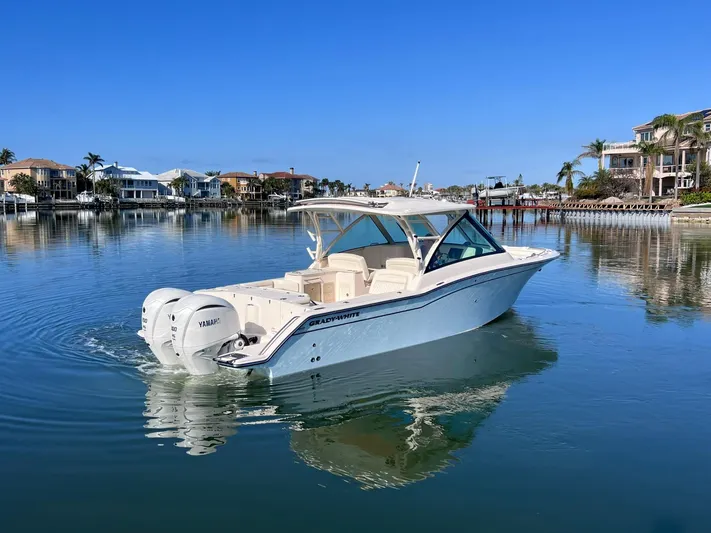 Yacht Photos Pics 2023 Grady-White Freedom 325 boat on calm water, with waterfront homes in the background.