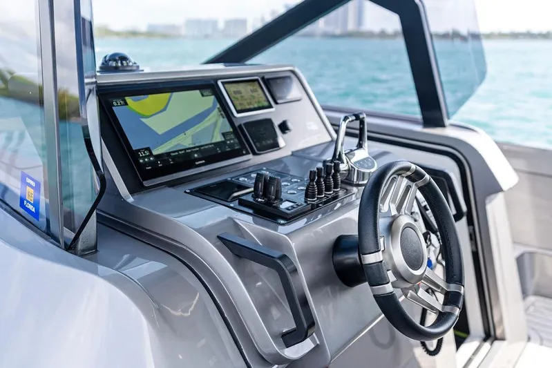 Mako Yacht Photos Pics 2024 Maori M46 boat dashboard with navigation controls and steering wheel, overlooking the ocean.