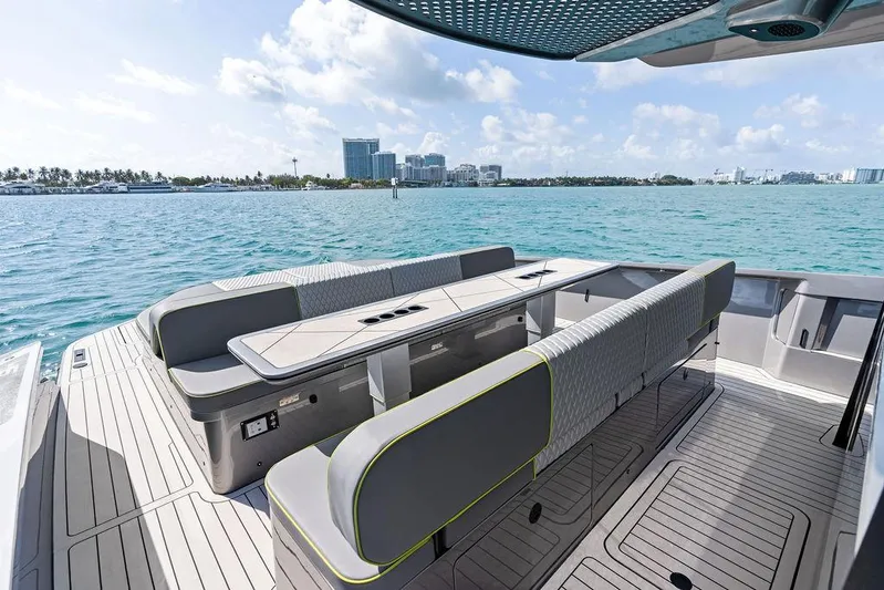 Mako Yacht Photos Pics Luxurious 2024 Maori M46 yacht deck with modern seating, overlooking a scenic waterfront cityscape.