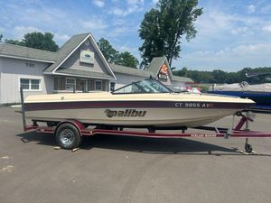 1999 Malibu Sunsetter VLX boat on trailer, parked outside a building on a sunny day.