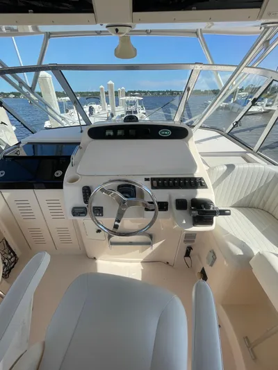 Working Girl Yacht Photos Pics 2008 Grady-White Open Express boat helm with steering wheel and controls, docked by the water.