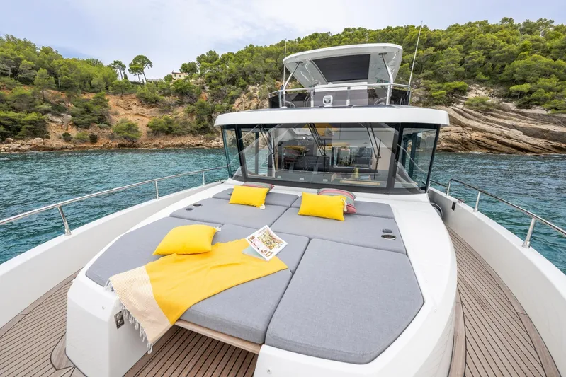  Yacht Photos Pics 2025 Beneteau Swift Trawler 54 with sun deck, yellow cushions, and scenic coastal backdrop.