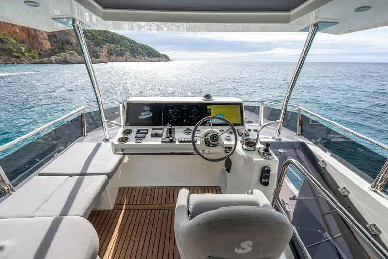  Yacht Photos Pics 2025 Beneteau Swift Trawler 54 helm with ocean view, featuring modern navigation controls.