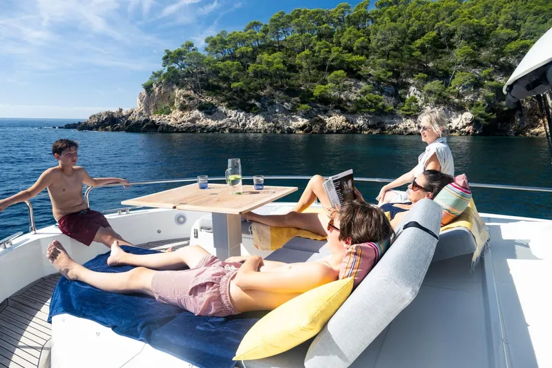  Yacht Photos Pics People relaxing on a 2025 Beneteau Swift Trawler 54, enjoying a scenic coastal view.