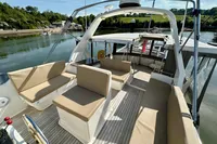 Spacious deck of 1990 Trader 41 + 2 Sundeck yacht with beige seating, docked by a scenic river.