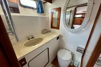 1990 Trader 41 + 2 Sundeck yacht bathroom with sink, toilet, mirror, and window.
