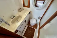 1990 Trader 41 + 2 Sundeck yacht bathroom with sink, toilet, and wooden flooring.
