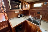 1990 Trader 41 + 2 Sundeck yacht kitchen with wooden cabinetry, dual sink, and microwave.