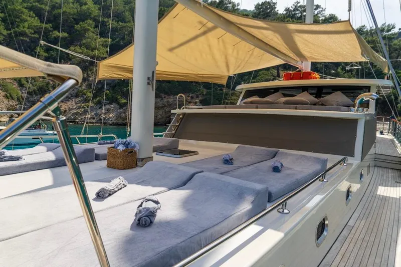 Yacht Photos Pics Luxurious 2022 Gulet 24m yacht deck with sunbeds and canopy, surrounded by scenic greenery.