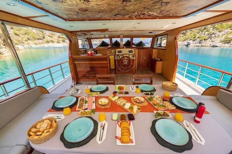 Yacht Photos Pics Luxurious dining setup on a 2022 Gulet 24m yacht, overlooking serene turquoise waters.