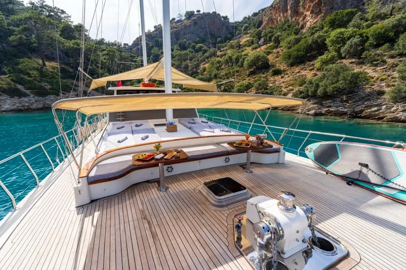  Yacht Photos Pics Luxurious 2022 Gulet 24m yacht deck with sunbeds, turquoise water, and scenic cliffs.