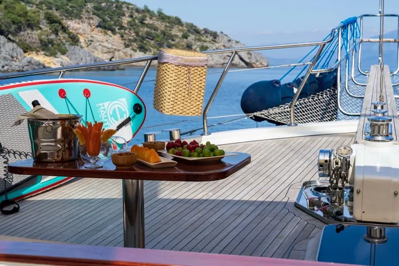  Yacht Photos Pics Luxurious 2022 Gulet yacht deck with refreshments, paddleboard, and scenic coastal view.
