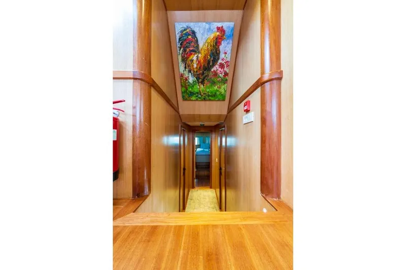  Yacht Photos Pics Wood-paneled hallway on 2022 Gulet 24m yacht, featuring vibrant rooster artwork.