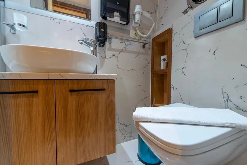  Yacht Photos Pics Modern bathroom on 2022 Gulet 24m yacht with marble accents and wooden cabinetry.