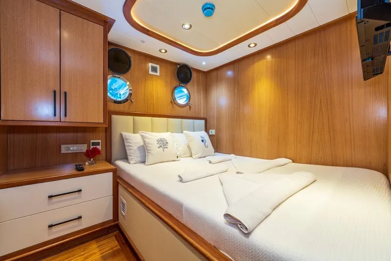  Yacht Photos Pics Luxurious cabin interior of 2022 Gulet 24 m yacht with wood paneling and cozy bedding.