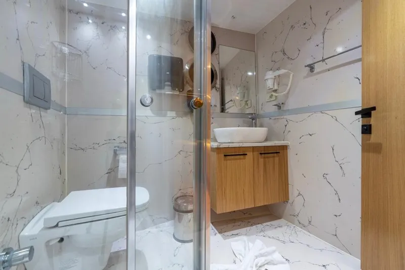  Yacht Photos Pics Modern bathroom on 2022 Gulet 24 m yacht with marble walls and wooden cabinetry.