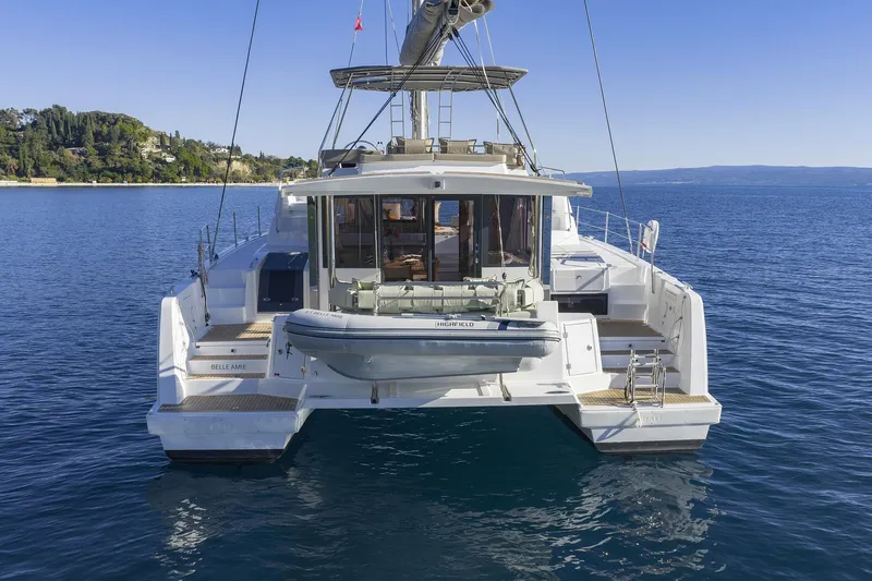 Belle Amie Yacht Photos Pics 2025 Bali 4.6 catamaran on serene blue waters, rear view with dinghy.