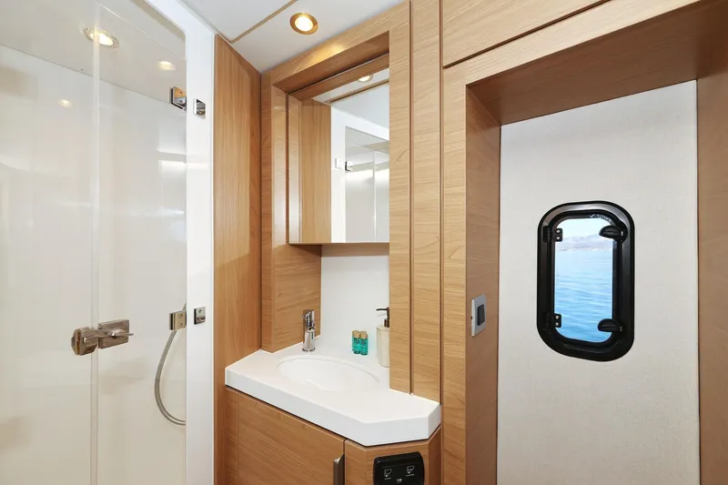 Belle Amie Yacht Photos Pics Modern yacht bathroom with wooden accents, featuring a shower and ocean-view window. Bali 4.6, 2025 model.