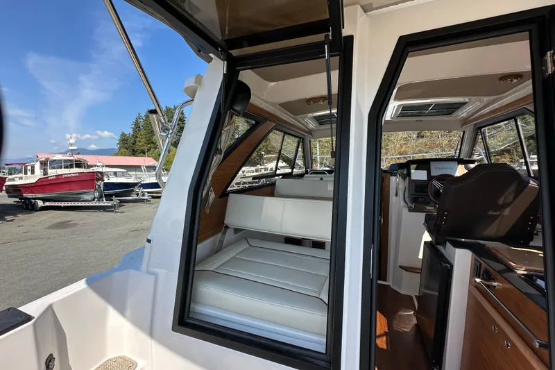  Yacht Photos Pics 2026 Cutwater C-248 Coupe interior with seating and helm, docked near other boats.