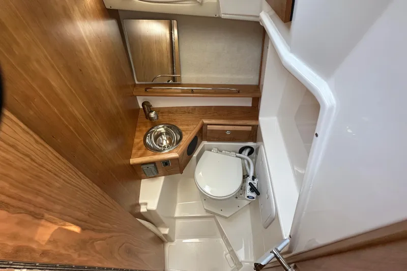  Yacht Photos Pics 2026 Cutwater C-248 Coupe bathroom with compact sink, toilet, and wooden accents.