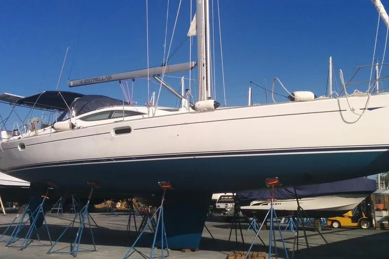 4 Estrellas Yacht Photos Pics 2006 Jeanneau Sun Odyssey 49 DS sailboat on stands, clear blue sky background.