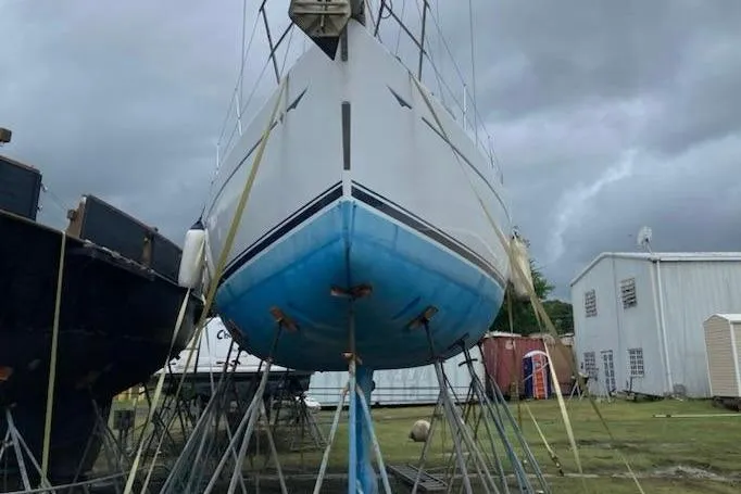4 Estrellas Yacht Photos Pics 2006 Jeanneau Sun Odyssey 49 DS sailboat on stands, cloudy sky background.