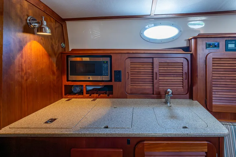 Gracious Yacht Photos Pics 2018 Hinckley Picnic Boat 37 MKIII interior with kitchenette, featuring microwave and wooden cabinetry.
