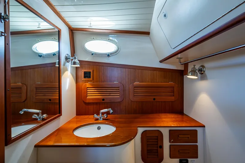 Gracious Yacht Photos Pics Elegant wooden bathroom interior of 2018 Hinckley Picnic Boat 37 MKIII with sink and mirror.