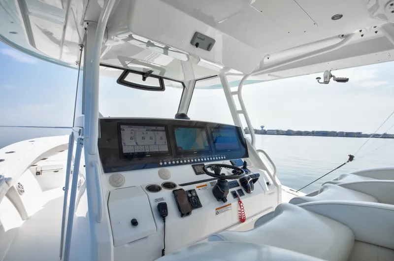  Yacht Photos Pics 2021 Regulator 41 boat cockpit with advanced navigation system and steering wheel, overlooking calm waters.