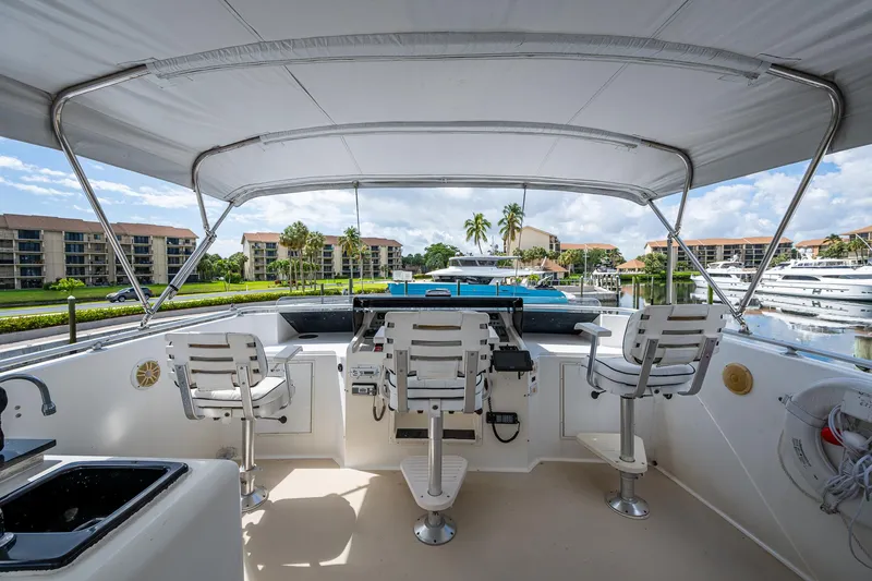 Mi Jule Yacht Photos Pics 1991 Viking 65 Motor Yacht helm with seating, docked in a marina, under a canopy.