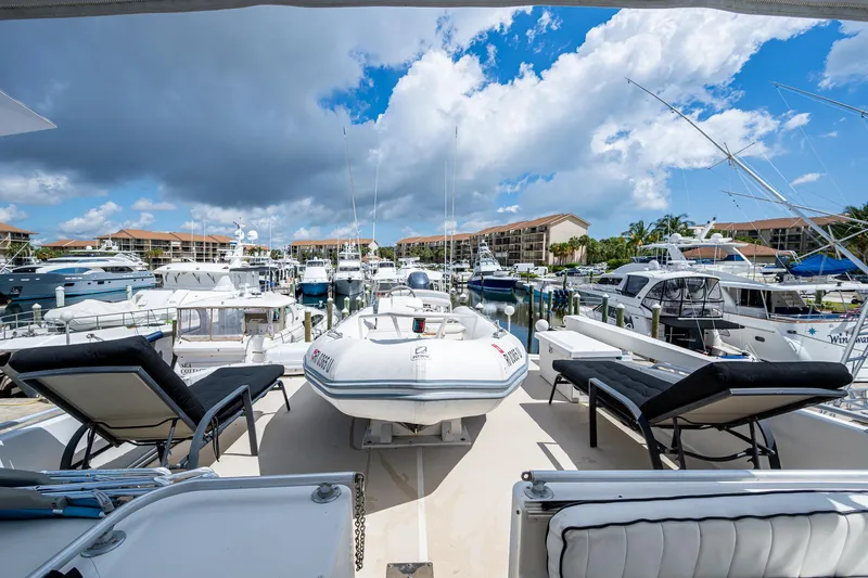 Mi Jule Yacht Photos Pics 1991 Viking 65 Motor Yacht at marina, featuring sun loungers and inflatable boat under cloudy sky.
