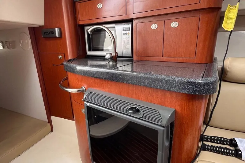  Yacht Photos Pics 2006 Boston Whaler 305 Conquest cabin interior with kitchenette, featuring wood cabinetry and modern appliances.