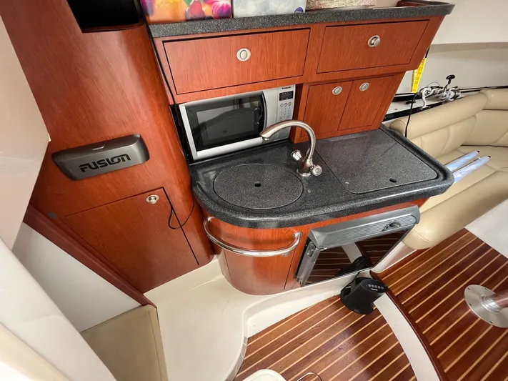  Yacht Photos Pics 2006 Boston Whaler 305 Conquest interior with kitchenette, featuring sink, microwave, and wooden cabinetry.
