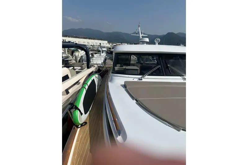  Yacht Photos Pics 2005 Mochi Dolphin 51 yacht docked with paddleboard on deck, mountains in background.