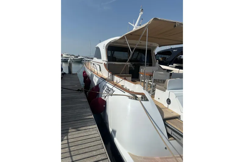  Yacht Photos Pics 2005 Mochi Dolphin 51 yacht docked at marina, featuring spacious deck and canopy.