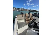 2023 Quicksilver Activ 675 Open boat interior with seating, steering wheel, and scenic harbor view.