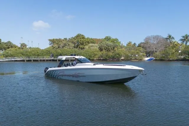 Yacht Photos Pics 2025 Cigarette 42' Auroris boat cruising on a calm lake with lush greenery.