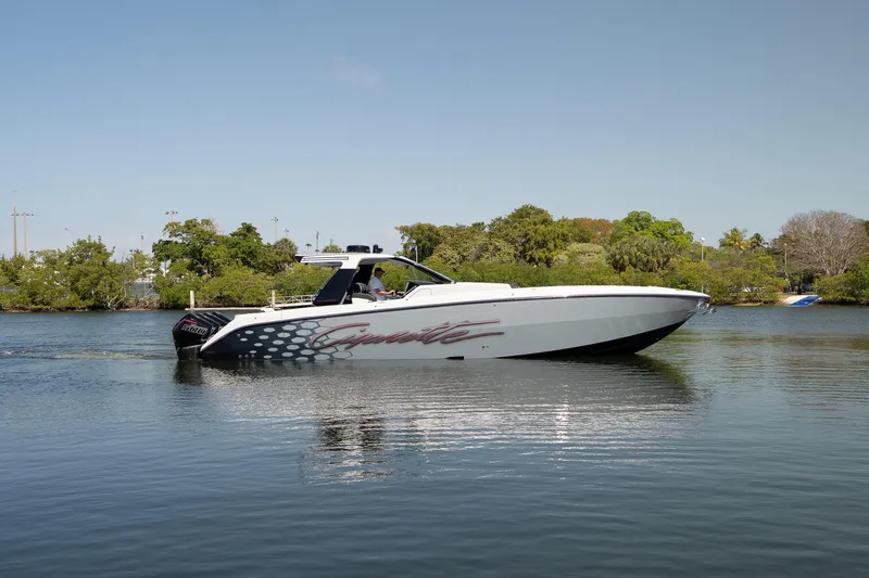  Yacht Photos Pics 2025 Cigarette 42' Auroris boat cruising on a calm lake with lush greenery.