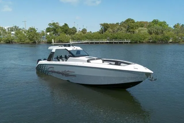  Yacht Photos Pics 2025 Cigarette 42' Auroris boat on calm water, surrounded by lush greenery.