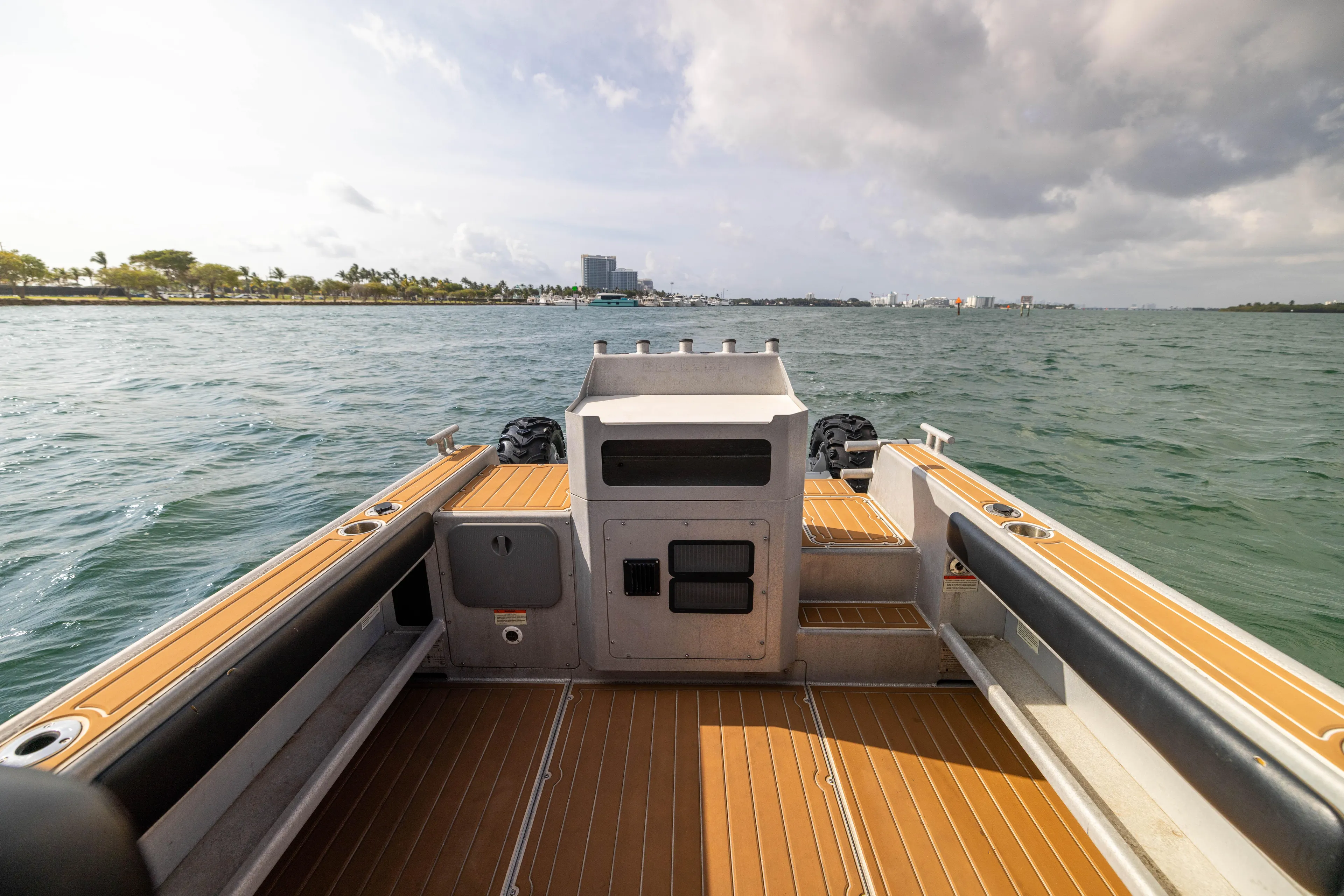 Latitude Yacht Photos Pics Sealegs 8.5M 2022 boat on water, wooden deck, cloudy sky, distant shoreline.