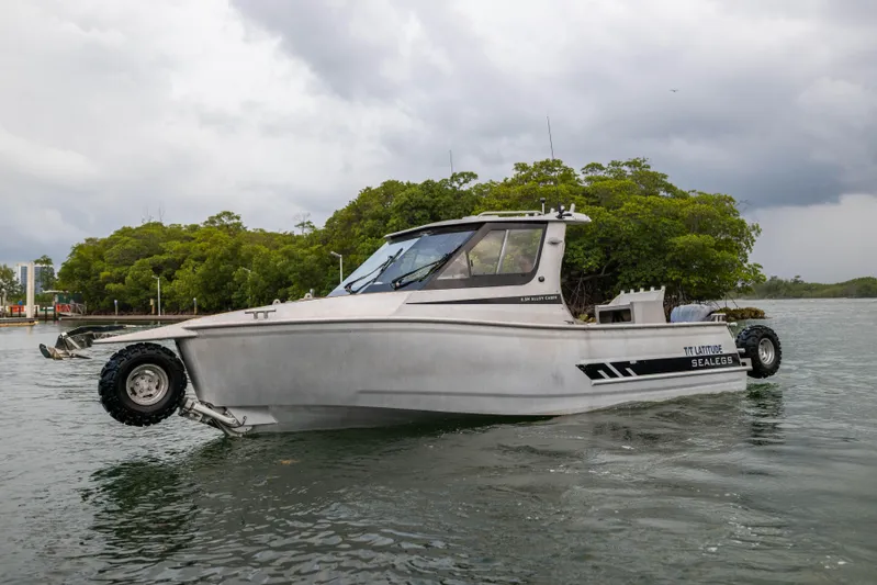 Latitude Yacht Photos Pics Amphibious Sealegs 8.5M boat, 2022 model, on water with wheels extended, cloudy sky background.