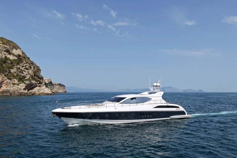 @last Yacht Photos Pics Luxury yacht Leopard 24 (2003) cruising near rocky coastline under clear blue sky.