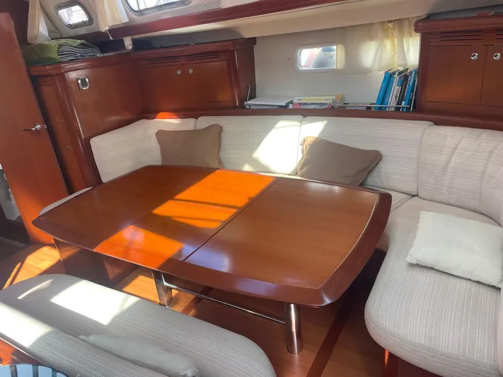  Yacht Photos Pics Interior of 2006 Beneteau Oceanis Clipper 523 with wooden table and cushioned seating.