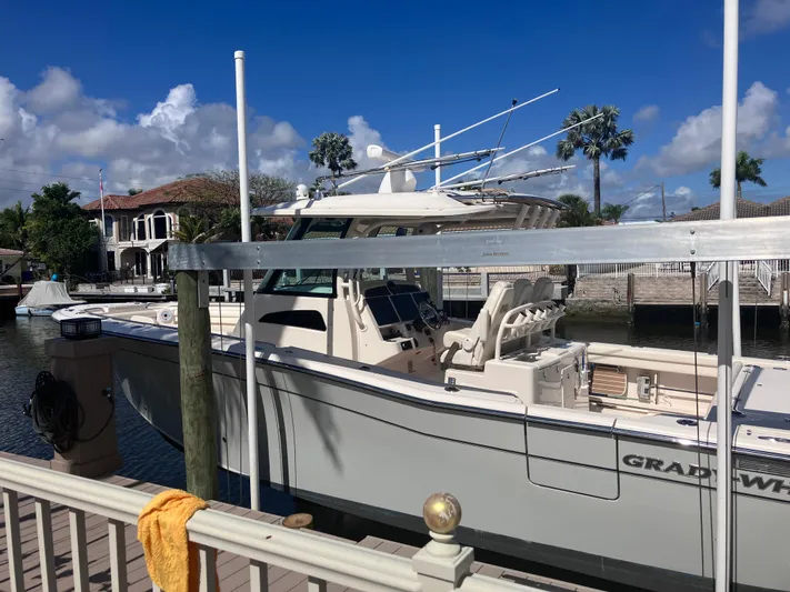  Yacht Photos Pics 2020 Grady-White Canyon 336 boat docked by waterfront homes under a clear blue sky.