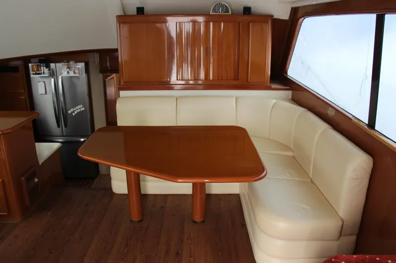 Galatea Yacht Photos Pics Luxurious yacht interior with wooden table, cream leather seating, and modern kitchen appliances.