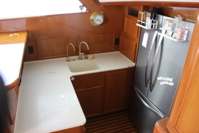 Galatea Yacht Photos Pics Small yacht kitchen with wooden cabinets, stainless steel fridge, and sink. Post 50, year 2000.